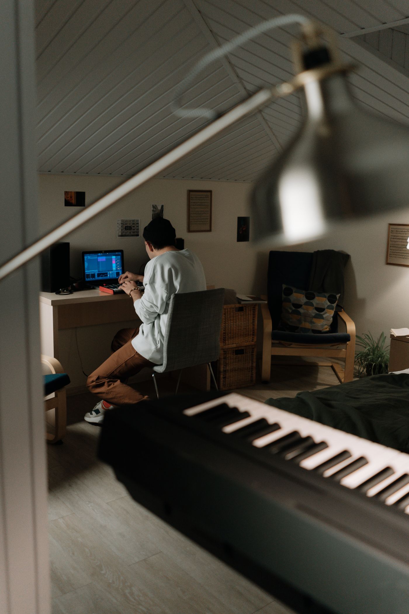 A musician working with a computer and keyboard in a home studio