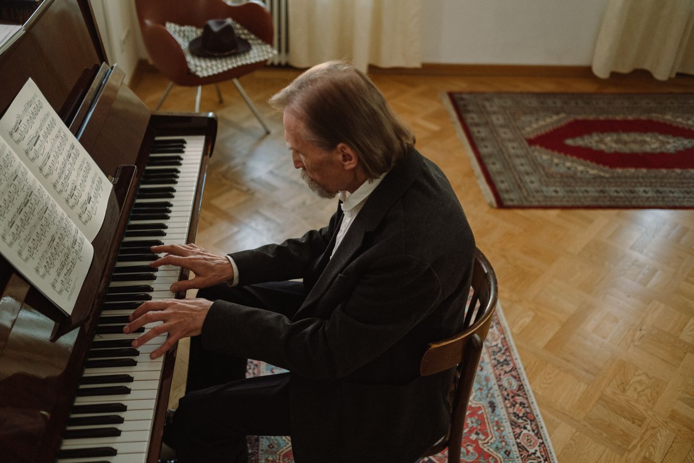 A pianist seated at a piano in a warmly lit room