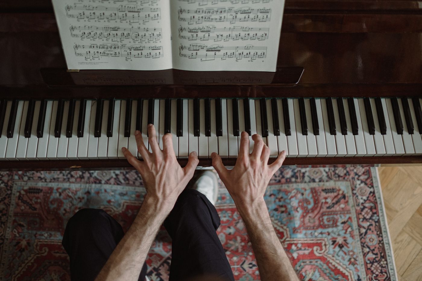 An overhead view of hands playing a piano