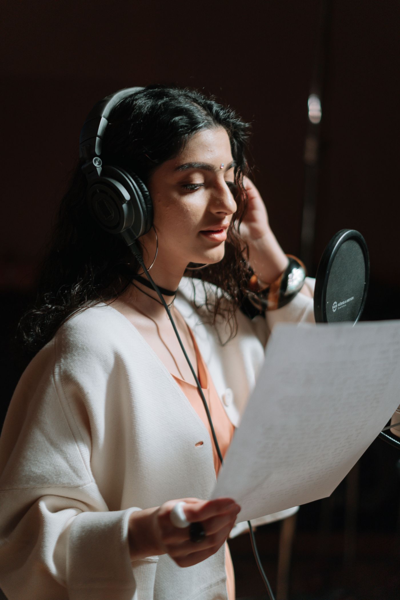A singer performing beside a studio microphone and pop filter