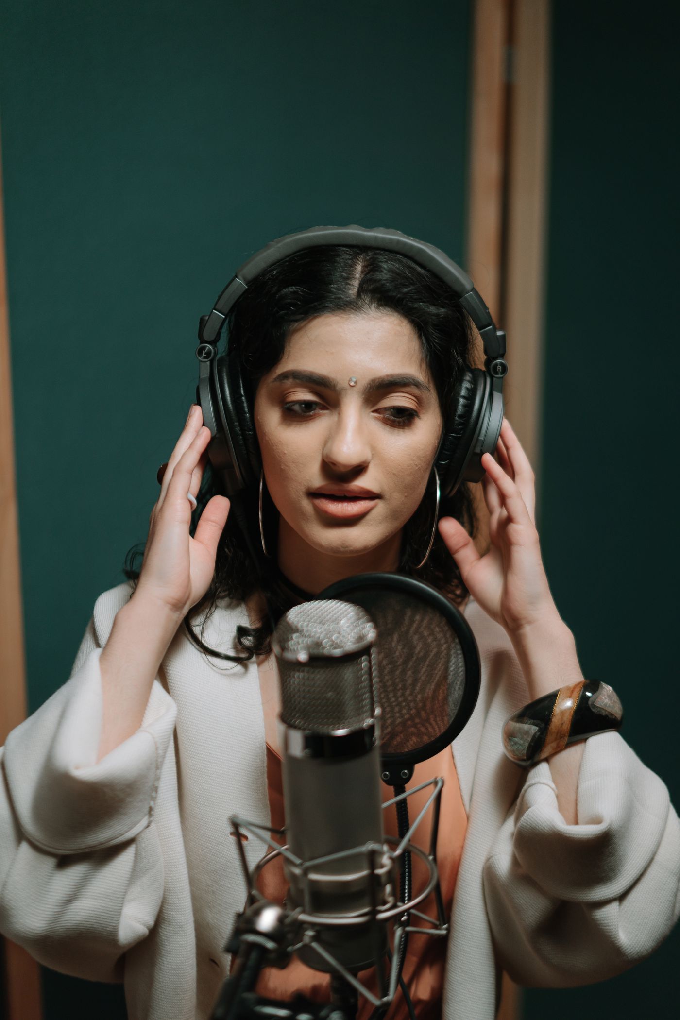 A singer recording with headphones and a microphone
