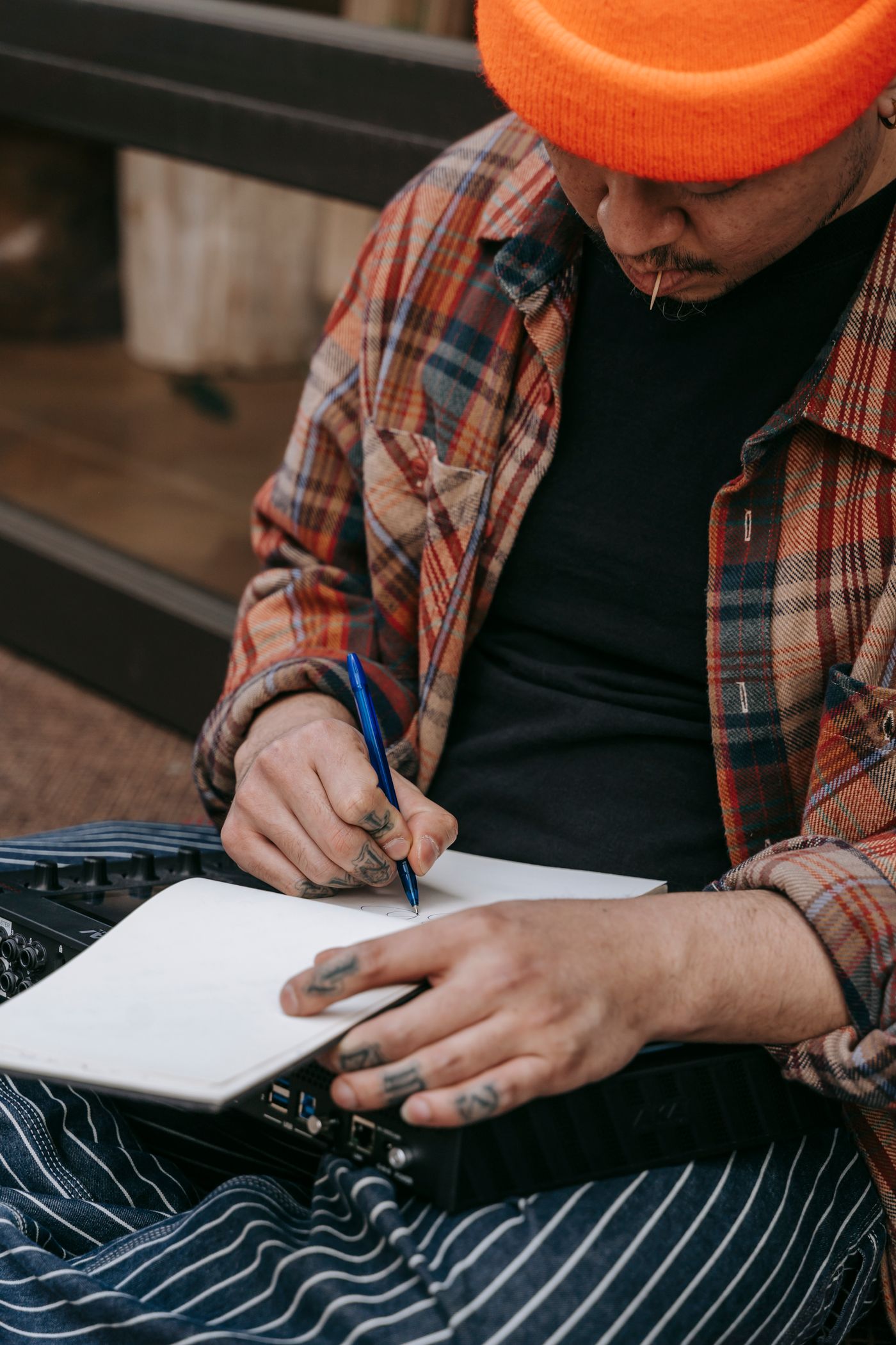 A musician writing outdoors with a guitar bag nearby