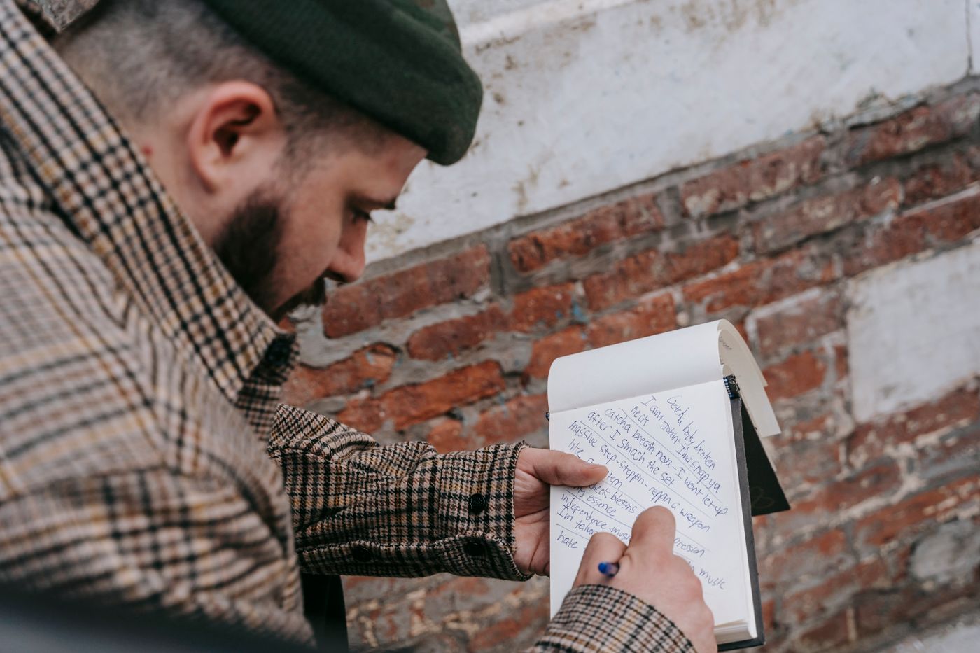A musician writing lyrics beside a brick wall
