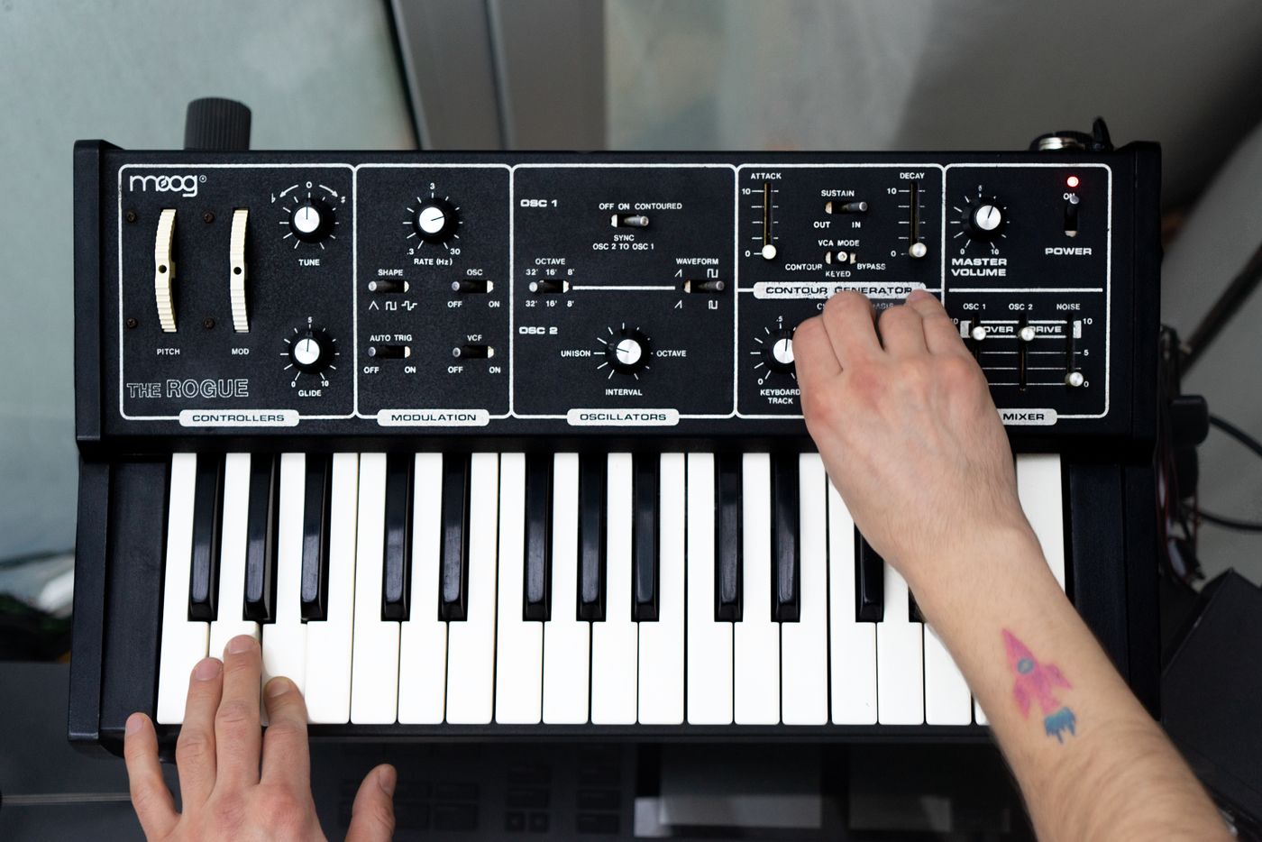 A musician playing a synthesizer and adjusting a sound