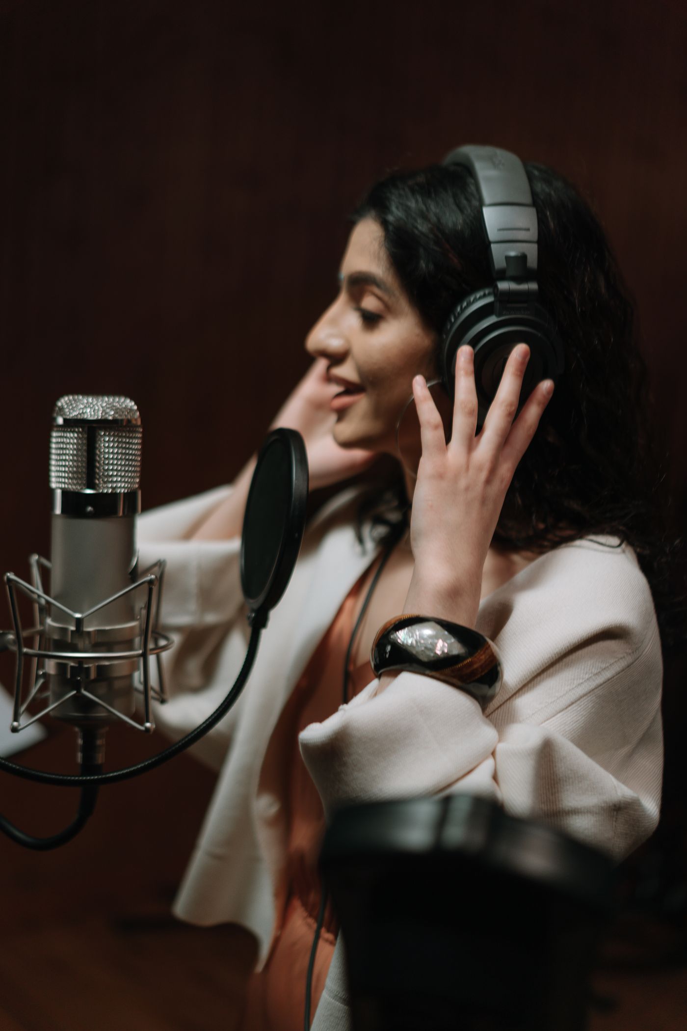 A singer recording at a microphone with headphones